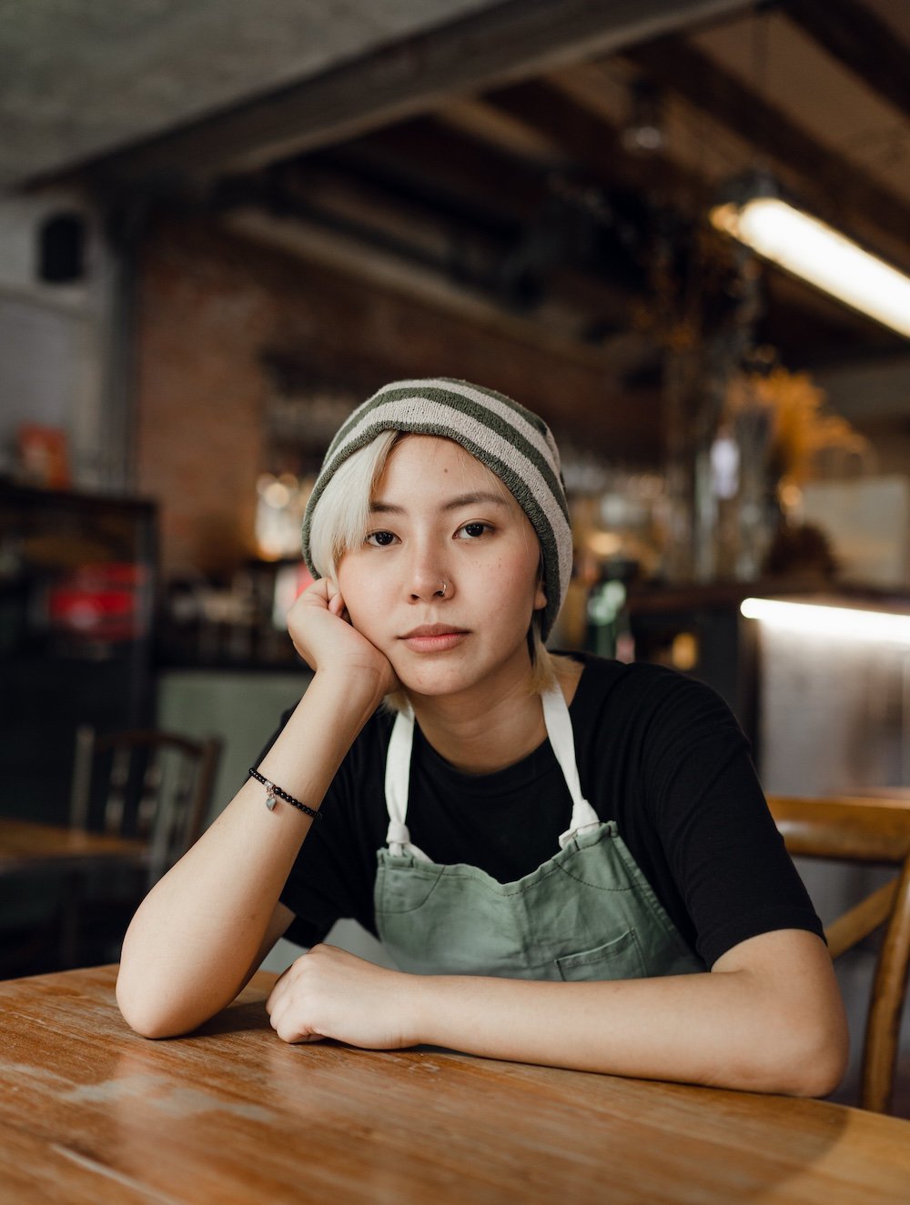 A woman in an apron in a café, staring at the camera